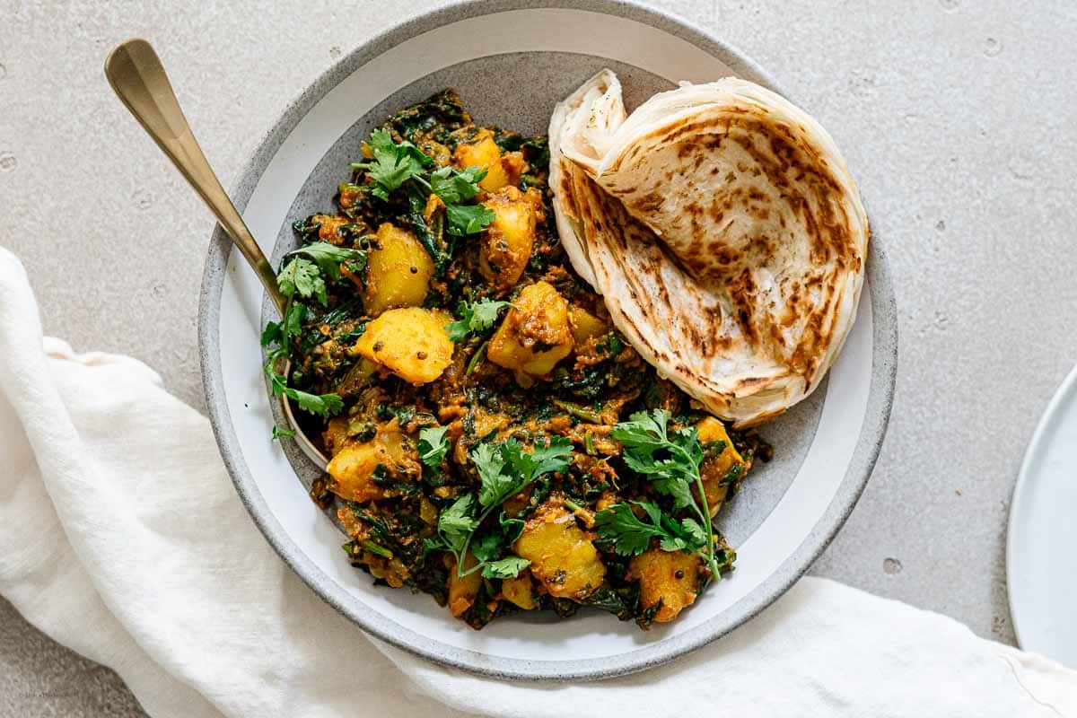 spinach and potato masala curry served with paratha