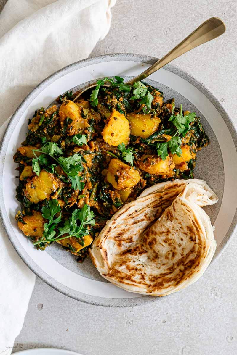 Indian spinach potato curry plated with paratha